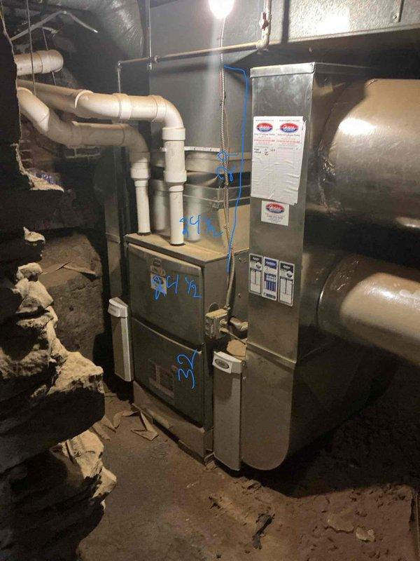 Conducted on-site assessment for air conditioning system addition to existing HVAC infrastructure. Evaluated current gray metal furnace unit with existing white PVC venting configuration and assessed basement mechanical room layout for AC integration compatibility. Documented existing ductwork system, including metallic supply ducts and flexible duct runs, to determine capacity for cooling system tie-in and verified adequate space for condenser unit placement and refrigerant line routing.