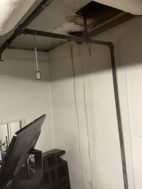 Responded to emergency call for leaking pipe in century-old residential property. Upon arrival, identified active water leak in exposed plumbing system located in basement area near ceiling joists. Documented extensive water damage including brown staining on walls and ceiling surfaces, with visible moisture intrusion through access panel opening. Coordinated with property owner regarding municipal water company shut-off requirements prior to commencing repairs. Assessed aging pipe infrastructure running along upper wall and ceiling sections in finished basement living space. Photographed damage extent and leak source for documentation purposes. Repair work required 5-hour estimated completion time pending water service shut-off coordination.