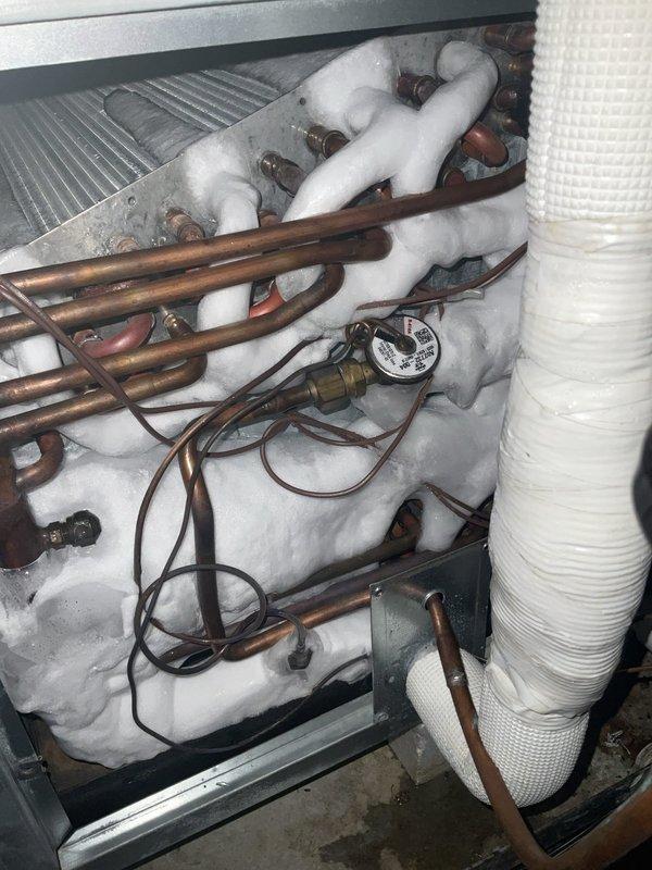 # HVAC Service Report

Responded to no cooling complaint on 1-2 year old air conditioning system. Found extensive ice buildup on evaporator coil and refrigerant lines during inspection. Connected refrigerant manifold gauges to diagnose system pressures and temperatures, which confirmed abnormal operating conditions causing the freeze-up. Primary issue identified as restricted airflow across evaporator coil leading to ice formation on copper tubing and coil surfaces. System required defrosting before proper diagnosis and correction of underlying cause could be completed.