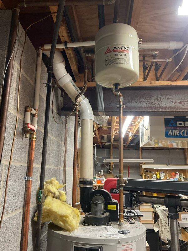 Completed free estimate for water heater replacement in residential basement utility area. Assessed existing white cylindrical tanked water heater installation with connected expansion tank, copper supply lines, PVC venting system, and associated plumbing components. Documented current system configuration including AMTROL expansion tank mounted to ceiling joists, pressure relief valve, and existing piping layout. Provided recommendations for complete water heater replacement at scheduled 8am appointment.