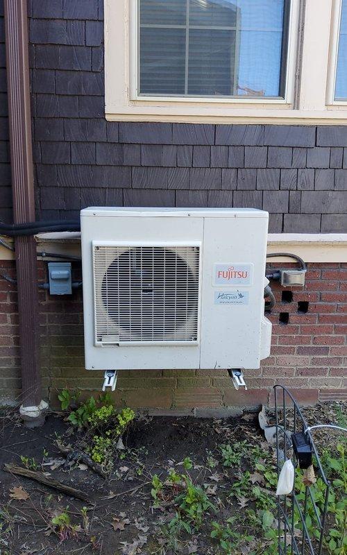 Completed annual preventive maintenance on Fujitsu Halcyon mini-split heat pump system. Inspected outdoor condenser unit mounted on exterior wall, verified secure mounting brackets, checked refrigerant line connections, and confirmed proper drainage. Evaluated indoor wall-mounted air handler in bay window area, tested operational performance of both heating and cooling modes, and documented system condition with photographs for maintenance records.