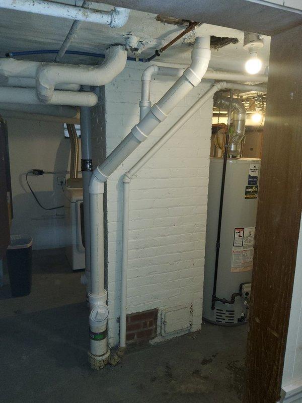 Responded to water leak call at century-old residential property. Inspected plumbing system throughout home, including basement mechanical room with exposed PVC drainage lines, water heater connections, and bathroom fixtures. Documented conditions with photographs showing plumbing infrastructure and potential leak sources in aging system.