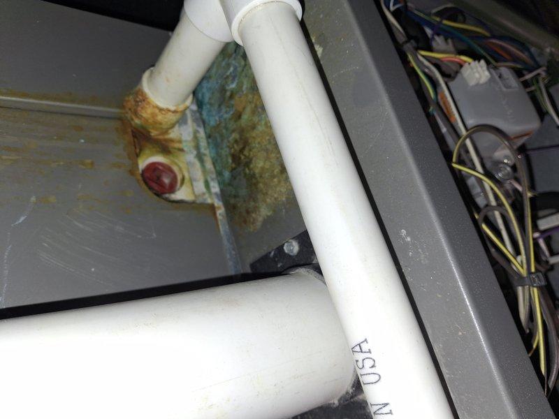 Responded to service call for HVAC unit with water intrusion damage. Upon inspection, found significant water damage to system components with extensive corrosion and rust buildup visible on drain assembly and metal surfaces. Documented condition of unit with photos showing corroded drain fixture with brownish-orange rust and green-blue patina indicating prolonged moisture exposure, compromised electrical components in close proximity to damaged areas, and oxidized copper refrigerant lines. Assessed overall system integrity and determined extent of water damage affecting both mechanical and electrical components. Provided diagnostic findings and recommendations for insurance claim purposes, including documentation of corroded drain assembly, affected wiring, and compromised unit housing requiring evaluation for repair versus replacement options.