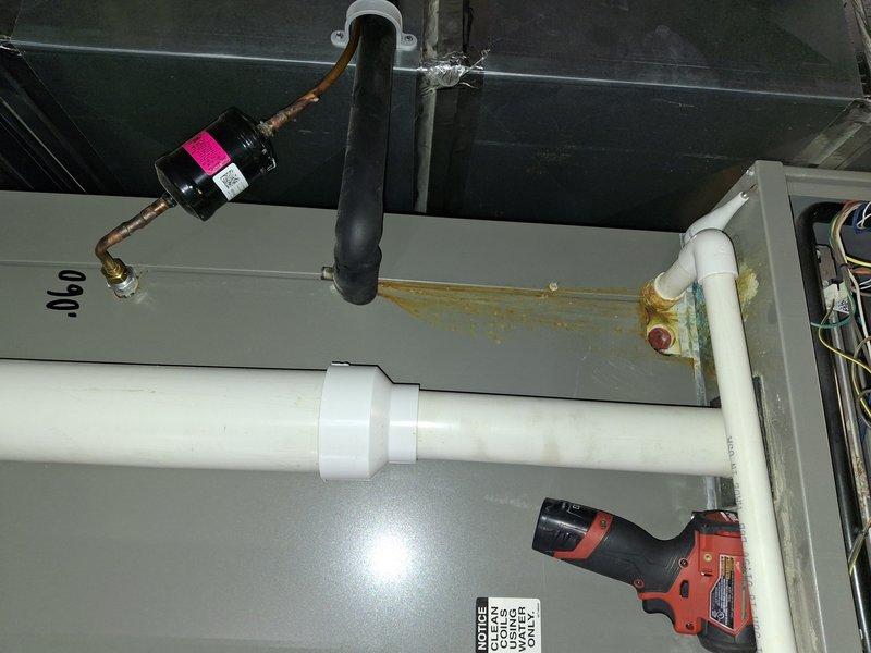 Responded to service call for HVAC unit with water intrusion damage. Upon inspection, found significant water damage to system components with extensive corrosion and rust buildup visible on drain assembly and metal surfaces. Documented condition of unit with photos showing corroded drain fixture with brownish-orange rust and green-blue patina indicating prolonged moisture exposure, compromised electrical components in close proximity to damaged areas, and oxidized copper refrigerant lines. Assessed overall system integrity and determined extent of water damage affecting both mechanical and electrical components. Provided diagnostic findings and recommendations for insurance claim purposes, including documentation of corroded drain assembly, affected wiring, and compromised unit housing requiring evaluation for repair versus replacement options.