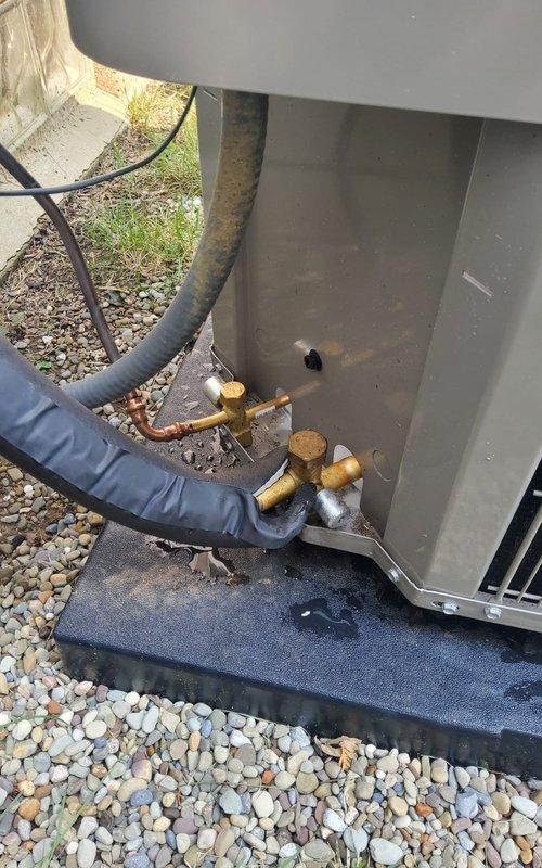 Responded to service call regarding deteriorating insulation on recently installed AC compressor. Upon arrival, performed thorough inspection of outdoor condensing unit and refrigerant line connections. Found black foam insulation on refrigerant lines showing signs of weathering and deterioration at base of unit. Documented condition of brass service valves, copper piping connections, and insulated refrigerant lines with photographs. Inspected unit mounting, gravel pad installation, and overall system installation quality to assess any additional concerns related to the reported deterioration.