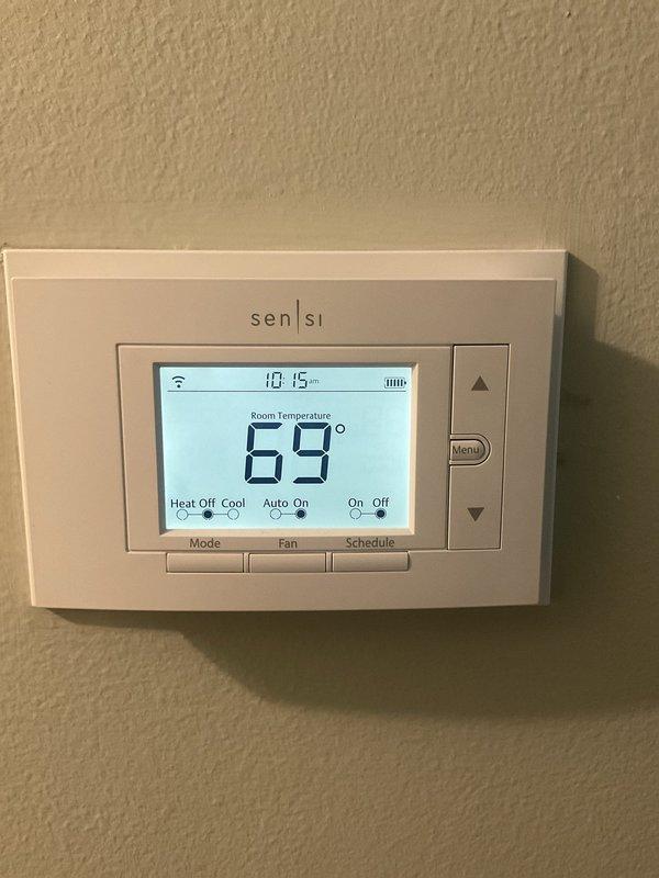 Responded to service call for one-year-old air conditioning system not operating properly. Upon arrival, verified thermostat settings on Sensi WiFi-enabled unit displaying 69°F room temperature with system in cooling mode. Inspected residential HVAC installation in mechanical room, including furnace unit with ductwork and electrical panel connections. Performed diagnostic evaluation of AC system, checked thermostat programming and wireless connectivity, verified proper power supply to equipment, and inspected electrical connections at breaker panel. Documented system configuration with photos showing thermostat interface and mechanical room equipment layout. System restored to proper cooling operation and customer contacted prior to arrival as requested.