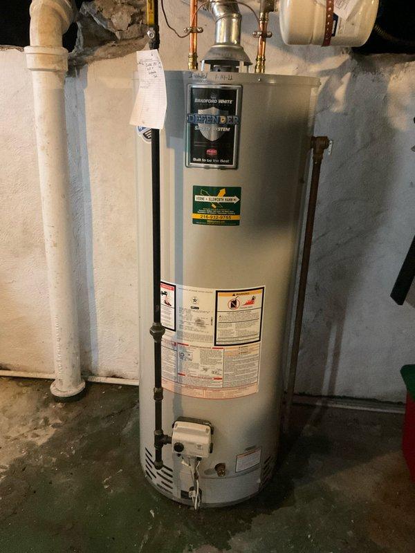Responded to emergency call for leaking water heater in 110-year-old residential property. Upon arrival, inspected four-year-old Bradford White tanked water heater installed in basement utility area and confirmed active water leak from unit. Documented existing installation configuration including copper supply lines with brass fittings, white PVC venting system, and current electrical connections via metallic flex conduit to junction box. Assessed leak severity and determined replacement necessary due to tank failure. Photographed existing installation setup, mechanical room conditions, and surrounding plumbing infrastructure for documentation purposes prior to recommending next steps for water heater replacement.