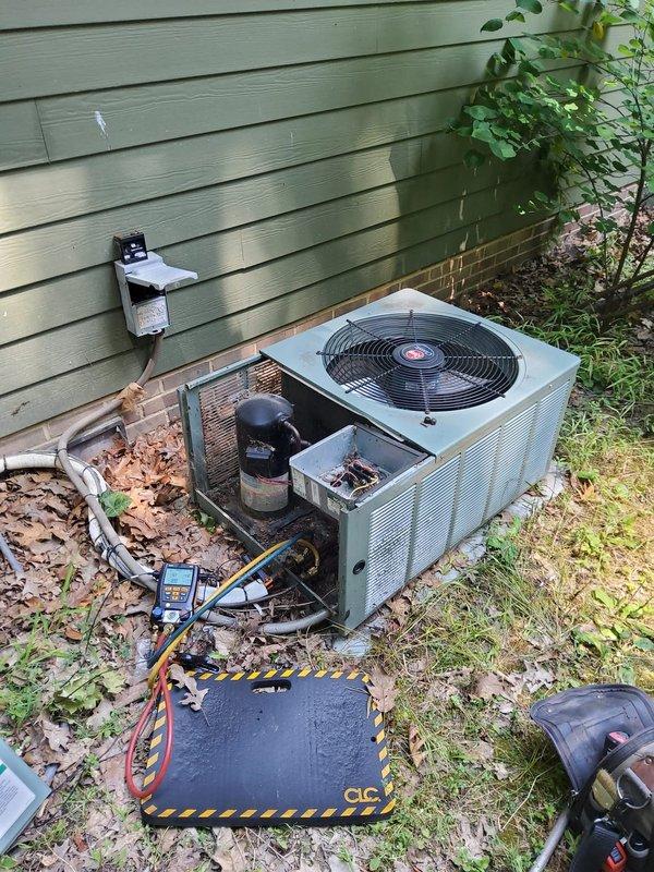 # HVAC Tune-Up Completed

Performed comprehensive preventive maintenance on a 20-year-old residential air conditioning system that was operating properly at time of service. Connected manifold gauges to measure refrigerant pressures and verify system charge levels. Inspected outdoor condenser unit, noting significant dirt and debris accumulation on coil fins and grille surfaces, as well as organic matter (leaves, grass clippings, pine needles) collected at base of unit. Cleaned condenser coil and removed debris from around equipment to restore proper airflow and heat transfer efficiency. Verified electrical connections at disconnect box and inspected refrigerant line sets running to home. System tested and confirmed operational following maintenance procedures.