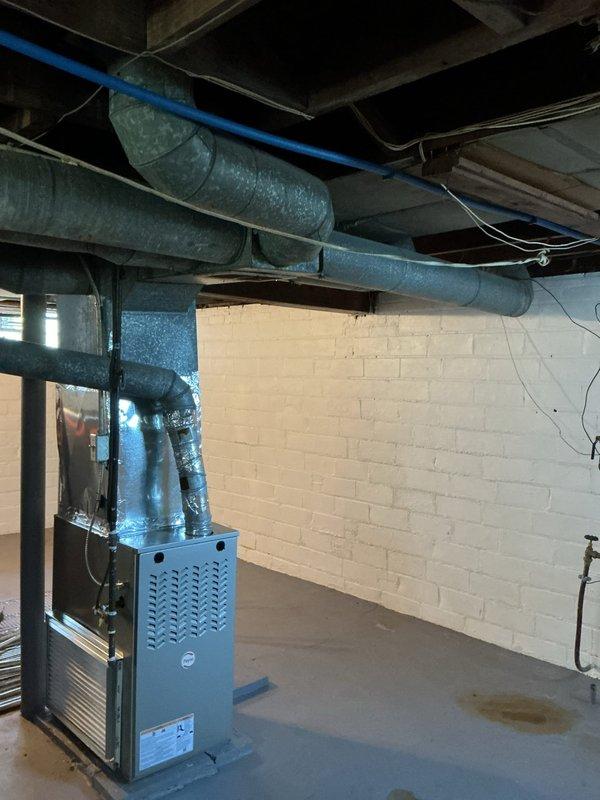 Conducted on-site evaluation for add-on air conditioning installation at rental property. Assessed existing furnace and ductwork infrastructure in basement mechanical room to determine compatibility and requirements for new AC system integration. Documented current HVAC setup including gray furnace unit with existing duct distribution system running through exposed ceiling space. Evaluated floor register locations and airflow pathways in upper living areas to ensure proper cooling distribution. Provided estimate for complete air conditioning system addition including outdoor condensing unit, evaporator coil installation, refrigerant line set, electrical connections, and integration with existing forced-air heating system.