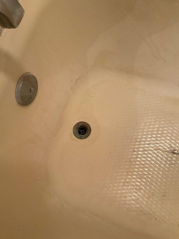 Responded to emergency call for bathtub drain malfunction causing water leak through ceiling below. Upon inspection, identified clogged drain assembly with corroded stopper mechanism preventing proper water drainage. Cleared obstruction, tested drain flow, and verified no further water penetration to lower level ceiling, resolving the immediate leak issue.