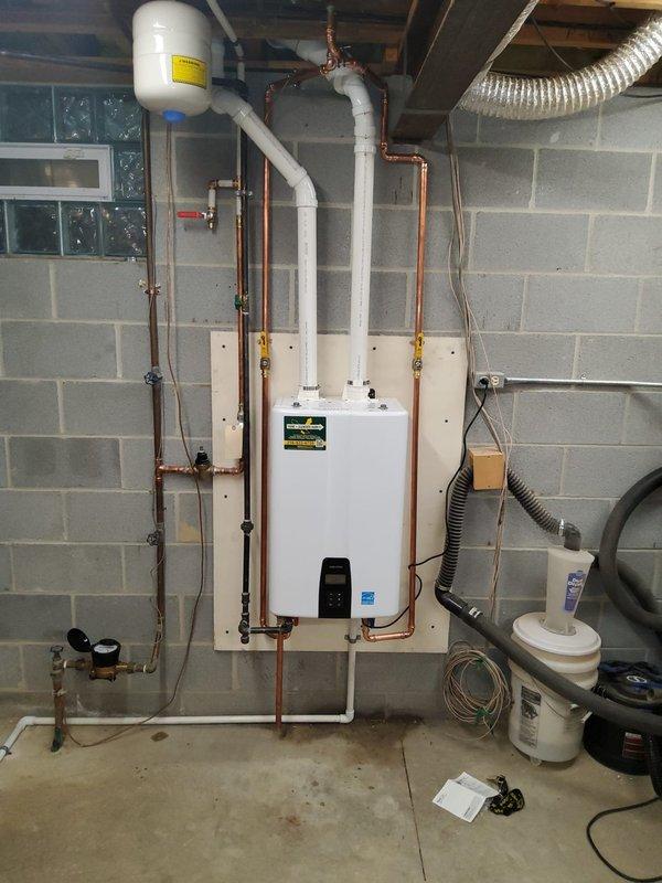 Removed existing conventional water heater and installed new wall-mounted tankless water heater unit in basement utility area. Completed all necessary copper pipe connections and routing, securing lines with proper brackets and support hardware. Installed expansion tank near ceiling with appropriate white PVC venting system connected to tankless unit exhaust. Integrated shut-off valves into copper piping system for service accessibility. Connected gas supply lines and verified proper ventilation configuration. Installed under-sink plumbing manifold with black flexible supply hoses and metal connector lines. Tested all connections for leaks, verified proper water flow and temperature output, and confirmed unit operation meets manufacturer specifications.