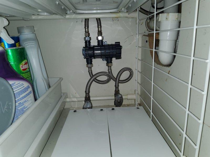 Removed existing conventional water heater and installed new wall-mounted tankless water heater unit in basement utility area. Completed all necessary copper pipe connections and routing, securing lines with proper brackets and support hardware. Installed expansion tank near ceiling with appropriate white PVC venting system connected to tankless unit exhaust. Integrated shut-off valves into copper piping system for service accessibility. Connected gas supply lines and verified proper ventilation configuration. Installed under-sink plumbing manifold with black flexible supply hoses and metal connector lines. Tested all connections for leaks, verified proper water flow and temperature output, and confirmed unit operation meets manufacturer specifications.
