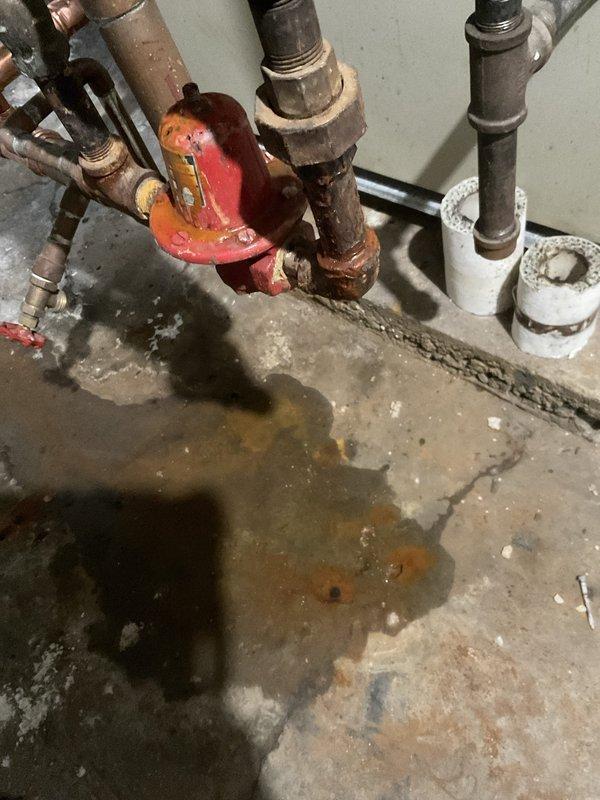 Responded to a residential plumbing emergency at a century-old home experiencing multiple water system failures. Upon arrival, assessed a severely corroded gate valve assembly with visible rust deterioration and active leaking at connection points, causing water damage and pooling on the concrete floor beneath the installation. Addressed a malfunctioning outdoor faucet that had ceased operation due to age-related component failure. Completed necessary repairs to the compromised valve system, replacing deteriorated sections of piping where corrosion had compromised structural integrity. Restored proper water flow and pressure throughout the affected areas, ensuring all fixtures returned to normal operation. Documented the existing plumbing infrastructure conditions, noting the mixed-material pipe configuration of aged metal and PVC components typical of retrofitted systems in historic properties.
