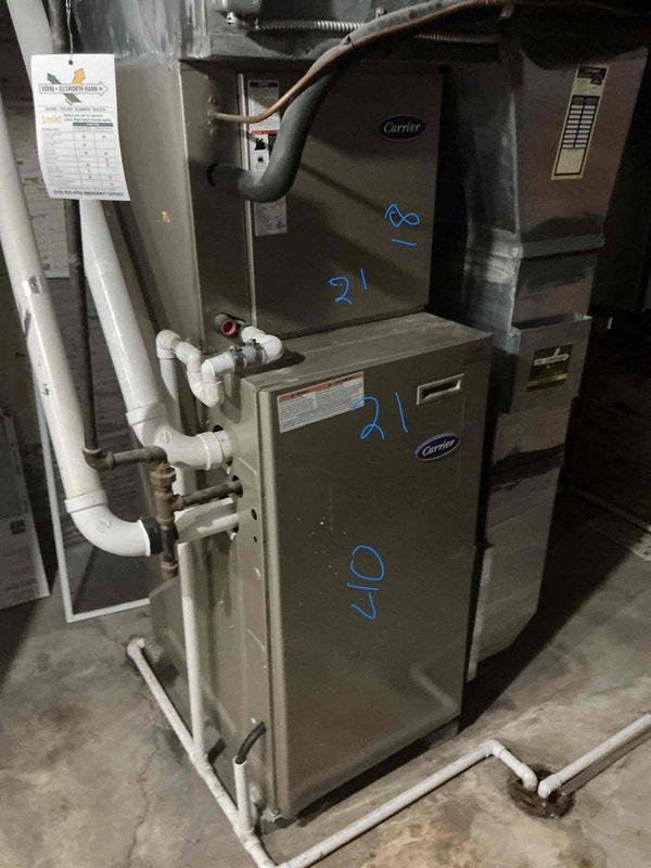 Responded to service call for 16-year-old Carrier central air conditioning system experiencing inadequate cooling and intermittent freezing of refrigerant line entering air handler, resulting in water accumulation. Conducted comprehensive system evaluation including inspection of indoor air handler unit and associated components, documented equipment condition with photographic evidence showing dual-cabinet configuration with visible service markings, PVC condensate drainage system, and refrigerant line connections. After thorough assessment of aging system performance issues and recurring freeze-up conditions, provided customer with complete replacement estimate for new HVAC system installation to resolve chronic operational deficiencies and restore proper climate control functionality.