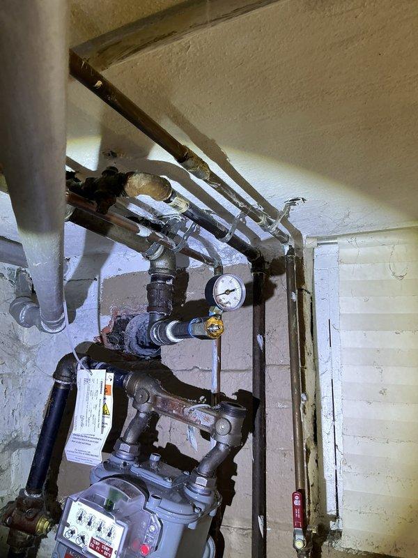 Responded to gas leak emergency at residential property where utility company identified three separate leak locations. Conducted comprehensive gas line pressure test of entire system, inspecting all exposed piping, valves, and connections in basement utility area. Located and repaired multiple leak points on aged natural gas distribution system, tested all repairs to ensure system integrity and safe operation, and documented conditions with photographic evidence of gas meter assembly and overhead piping configuration.