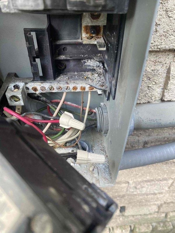 Responded to no cooling complaint on residential air conditioning system. Upon inspection, discovered severe corrosion and rust on electrical bus bar and terminals within outdoor disconnect panel, compromising electrical connections to condensing unit. Performed electrical testing with multimeter to verify power supply issues. Documented extensive deterioration of disconnect components showing heavy moisture intrusion and oxidation that prevented proper system operation.
