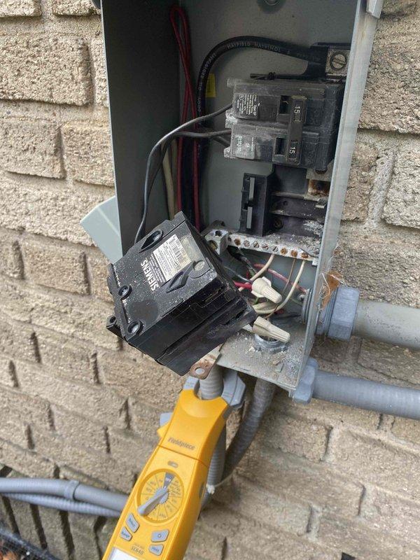 Responded to no cooling complaint on residential air conditioning system. Upon inspection, discovered severe corrosion and rust on electrical bus bar and terminals within outdoor disconnect panel, compromising electrical connections to condensing unit. Performed electrical testing with multimeter to verify power supply issues. Documented extensive deterioration of disconnect components showing heavy moisture intrusion and oxidation that prevented proper system operation.