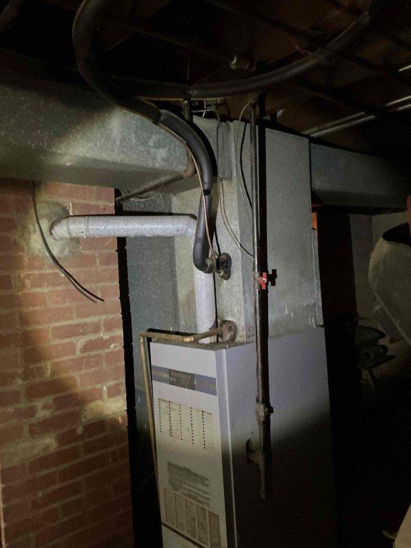 Conducted on-site evaluation of existing HVAC system in basement utility area for furnace and air conditioning replacement estimate. Inspected current vertical furnace unit, associated ductwork including overhead plenum and flexible ducting connections, electrical wiring, and PVC condensate drainage system. Documented equipment condition and installation configuration through photographic assessment to provide comprehensive replacement proposal.