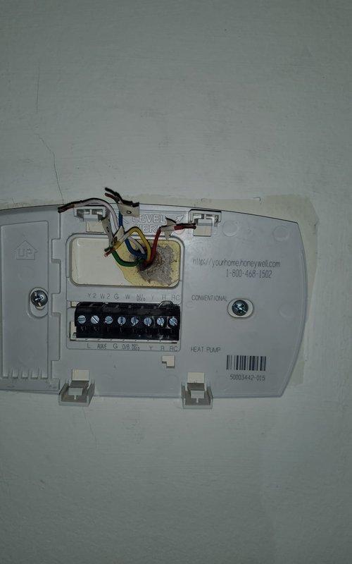 Returned to site to complete rewiring of HVAC system as previously scheduled. Accessed equipment compartment and verified all refrigerant line connections and electrical components. Completed proper wiring connections at thermostat base plate, ensuring all terminals (R, C, Y, W, G) were securely fastened per manufacturer specifications. Documented equipment condition with photos showing copper refrigerant lines, electrical relay components, and completed thermostat wiring configuration. System wiring now complete and ready for operational testing.
