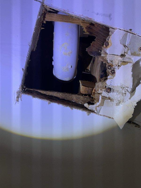 Responded to plumbing leak in 105-year-old residential property. Upon arrival, inspected ceiling damage revealing compromised structural framing and water-stained supply piping running through ceiling cavity. Ceiling opening exposed deteriorated wooden joists with visible moisture damage and discoloration on vertical pipe installation. 

Assessed basement floor drain system showing accumulated sediment and debris within drain bowl. Drain assembly exhibited signs of age-related wear consistent with property vintage. Inspected overhead wooden beam structure for moisture intrusion and verified integrity of plumbing penetrations. 

Documented existing conditions including ceiling water damage patterns, compromised drywall, and basement drainage components. Photographed affected areas for service records and future reference.