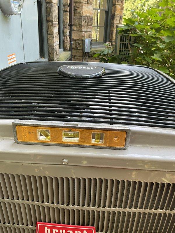 Leveled Bryant condenser unit to manufacturer specifications to prevent compressor damage and oil migration issues. Unit was found to be improperly positioned on pad, creating potential for premature equipment failure. Adjusted and stabilized condenser on concrete pad using proper leveling techniques, verified alignment with precision level tool to ensure optimal refrigerant flow and compressor longevity.