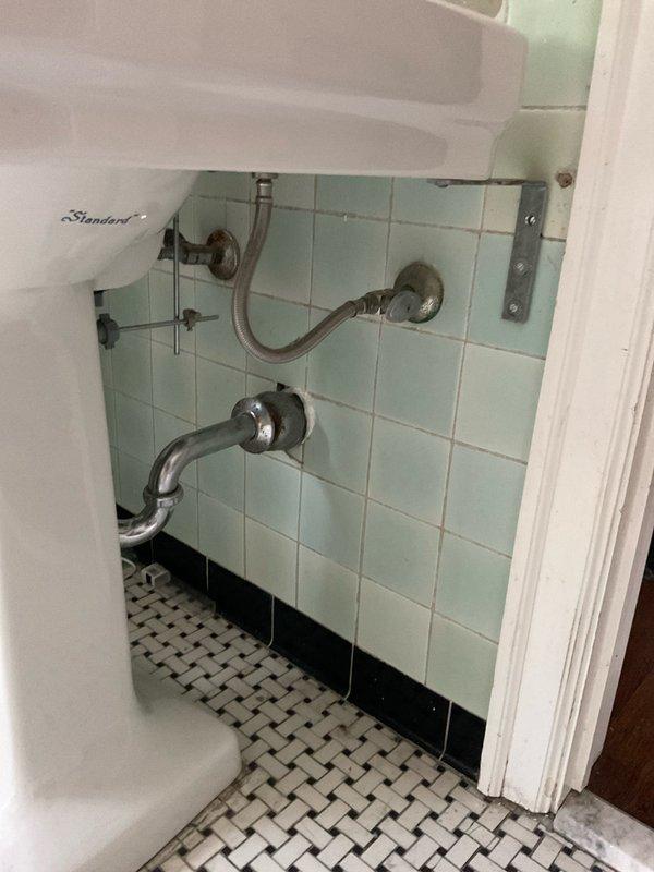 Responded to water leak originating from third-floor shower fixture with water penetrating through multiple floors to basement level. Upon arrival, inspected the identified shower faucet and associated plumbing connections. Examined vintage plumbing system consistent with the 111-year-old structure, including aged chrome drain pipes, flexible braided supply lines, and wall-mounted fixtures showing significant weathering and tarnish. Assessed the extent of water intrusion pathway from third floor through building envelope to basement. Isolated the leak source at the shower valve assembly and verified no additional leak points in adjacent bathroom fixtures or supply lines. Documented existing plumbing conditions including traditional pedestal sink connections and period-appropriate tile work. Completed necessary repairs to eliminate active water flow and restore proper fixture operation, preventing further water damage to lower levels.