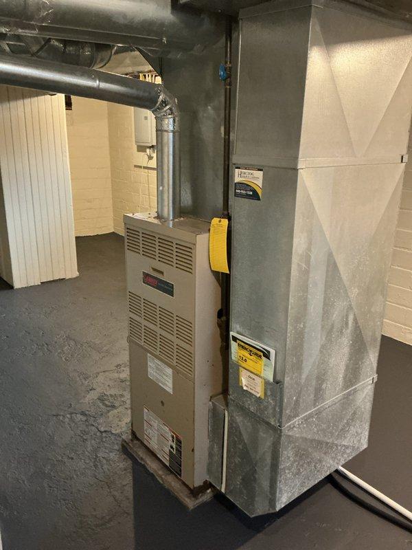 Conducted comprehensive evaluation of existing basement HVAC system for furnace and air conditioning replacement estimate. Documented current equipment configuration including aging furnace unit with vertical vent pipe and metal supply plenum showing significant wear, discoloration, and accumulated debris. Assessed mechanical room layout, existing ductwork connections, drainage systems, and utility clearances to determine replacement specifications and installation requirements.