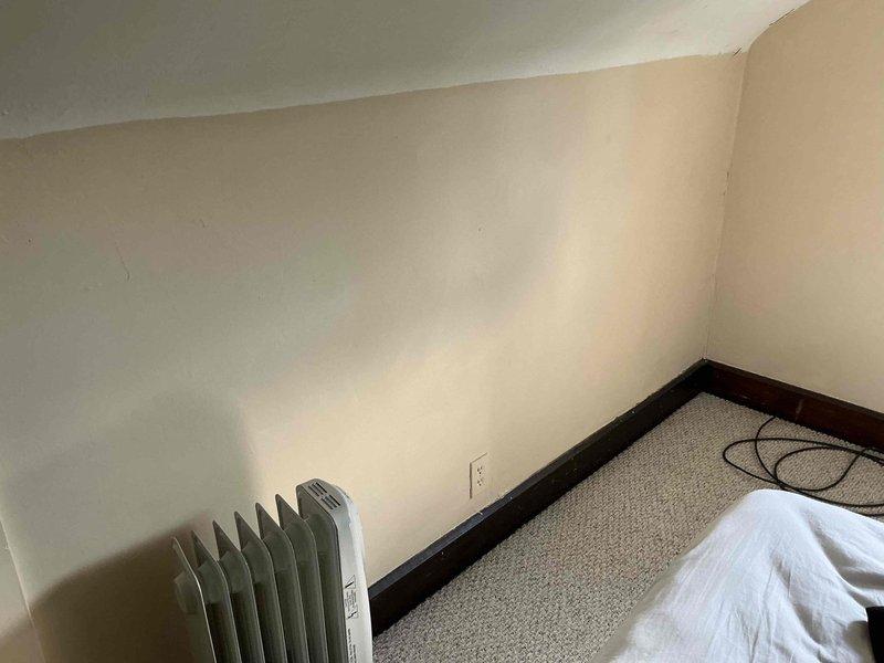Conducted on-site assessment for mini split installation in attic space. Evaluated existing heating system consisting of portable oil-filled radiators and documented current room conditions including electrical outlet locations, wall construction, and available mounting surfaces. Photographed installation area to determine optimal placement for indoor air handler unit and provided estimate for ductless mini split system.