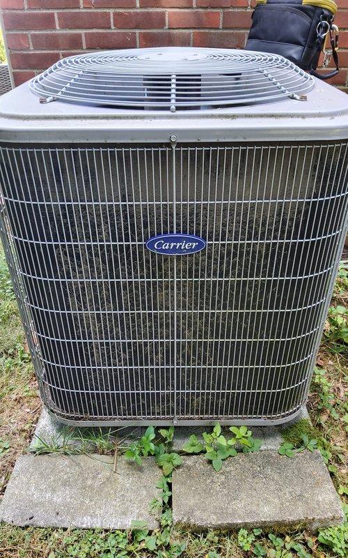 Performed comprehensive AC tune-up on Carrier outdoor condensing unit. Inspected all major components including compressor, condenser coil, fan motor, and electrical connections. Verified proper refrigerant pressures and system operation. Condenser coil showed moderate accumulation of debris between fins; cleaned coil to restore optimal airflow and heat transfer efficiency. Checked recently replaced capacitor for proper operation and secure mounting. Cleared vegetation growth from base of unit and around concrete pad to maintain adequate clearance. Tested system startup and shutdown sequences, confirmed proper amperage draw on all components. System operating within manufacturer specifications with no issues detected.