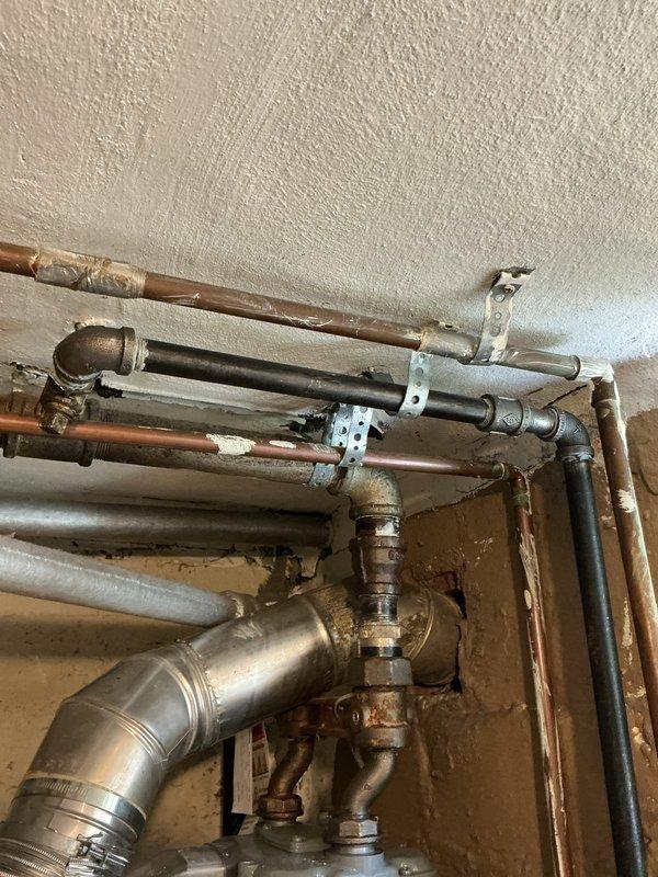 Responded to gas leak service call following utility company inspection and gas shutoff. Assessed existing gas line configuration from trunk line to dryer location, including compromised valve assembly requiring replacement. Evaluated scope of work for gas line re-piping as specified by utility company, including necessary appliance relocation to access and replace affected piping sections. Documented existing pipe conditions and valve assembly showing age-related deterioration. Site prepared for gas line replacement work to meet utility company requirements for service restoration.