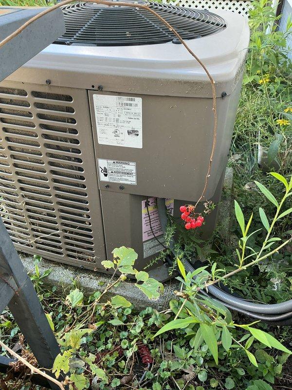 Responded to service call for 10-year-old air conditioning system not cooling and experiencing freeze-up conditions. Upon arrival, performed comprehensive diagnostic evaluation of both indoor and outdoor HVAC components. Inspected York furnace installation in basement mechanical room along with associated ductwork, refrigerant lines, and auxiliary equipment including dehumidifier and wall-mounted air handler. Evaluated outdoor condenser unit, noting overgrown vegetation surrounding equipment which can restrict airflow and reduce system efficiency. Documented current system conditions through photographic evidence showing complete HVAC installation layout and outdoor unit placement. Based on age of equipment, freeze-up symptoms, and overall system assessment, provided detailed estimate for complete HVAC system replacement to address cooling deficiencies and prevent future operational failures.