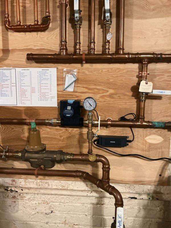 # Moen Flo Smart Water Monitor Installation

Completed installation of Moen Flo whole house smart water monitoring system on residential plumbing distribution panel. Integrated dual electronic monitoring devices into existing copper supply line configuration with brass fittings and pressure regulation components. Installed system pressure gauge for real-time monitoring capability, configured electronic sensors with proper wiring connections, and verified all connections for leak-free operation. Mounted installation documentation and spare components packet on service panel. System tested and operational, providing automated water flow monitoring and leak detection functionality for the entire household plumbing system.