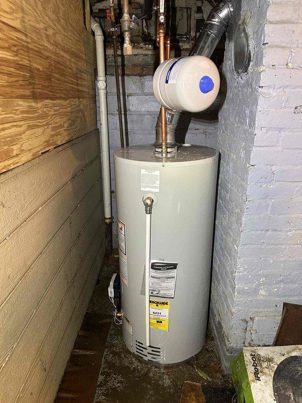 # HVAC Maintenance - Cooling System Service

Performed comprehensive maintenance inspection on residential cooling system located in basement utility area. Upon arrival, accessed mechanical room housing HVAC equipment alongside water heating system in confined space between wooden partition wall and painted brick foundation wall.

Conducted standard maintenance protocol including visual inspection of all accessible components. Examined refrigerant line connections, electrical connections, and condensate drain system. Verified proper clearances around equipment for adequate airflow and safe operation. Inspected ductwork connections including metallic supply plenum with curved transition section extending from air handler unit.

Documented equipment installation environment noting exposed ceiling joists, concrete flooring, and proximity to plumbing infrastructure including copper and PVC water supply lines. Observed humidifier or air quality equipment integrated with HVAC system, connect