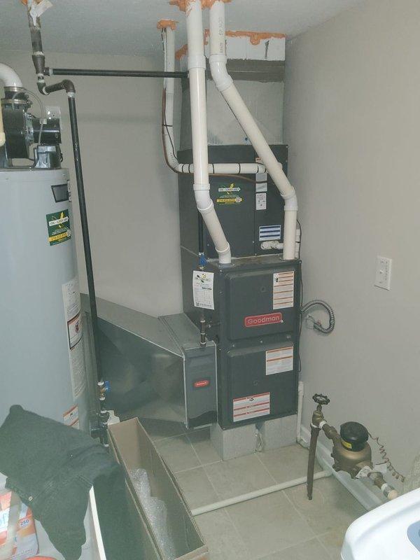 Responded to no cooling complaint on 10-year-old Goodman HVAC system where indoor fan was operating but unit was not producing cold air. Upon arrival, coordinated with multiple tenants on-site and performed diagnostic inspection of the furnace and air handler assembly located in utility room. Inspected outdoor condensing unit ventilation louvers and confirmed proper airflow through exterior grilles. Documented existing equipment conditions including water heater, furnace configuration, condensate pan positioning, and associated plumbing connections. System evaluation completed and photographic documentation captured for service records.