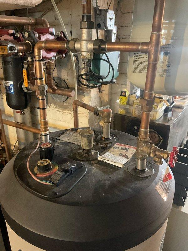 Responded to a leaking indirectly heated hot water storage tank in a century-old three-family residence. The tank is interconnected with the property's hot water boiler and heating system, serving two residential suites. Performed comprehensive annual inspection of the mechanical system, including evaluation of all copper piping connections, expansion tank, boiler interface, and associated plumbing infrastructure. Identified source of water leak at tank connections and executed necessary repairs to restore proper operation and eliminate water discharge to basement floor.