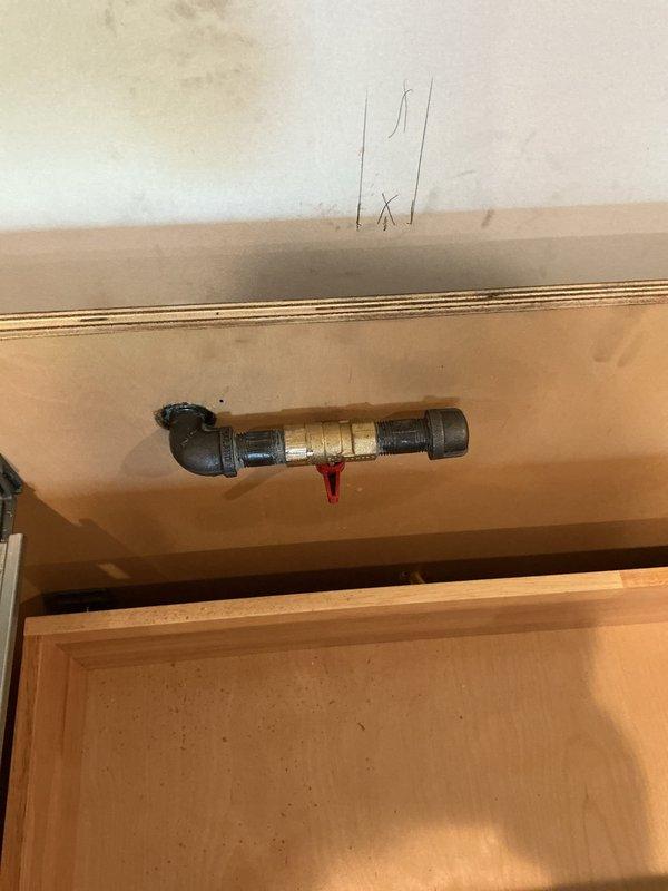 Completed plumbing installation for kitchen remodel, installing new supply lines with shut-off valve assembly under cabinet. Installed insulated refrigerant line and connected water supply piping with brass valve featuring accessible shut-off control for future maintenance access.