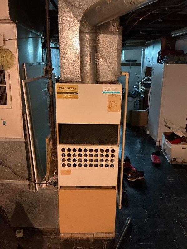 Conducted comprehensive HVAC system evaluation for equipment replacement estimate in residential basement mechanical room. Assessed existing furnace unit and ductwork configuration, documenting current system condition including aged insulation wrap on metal supply ducts and overall equipment layout. Photographed existing installation to provide detailed documentation for replacement proposal, capturing furnace specifications, duct connections, clearance requirements, and surrounding infrastructure including plumbing and electrical components.