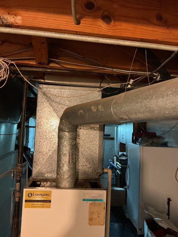 Conducted comprehensive HVAC system evaluation for equipment replacement estimate in residential basement mechanical room. Assessed existing furnace unit and ductwork configuration, documenting current system condition including aged insulation wrap on metal supply ducts and overall equipment layout. Photographed existing installation to provide detailed documentation for replacement proposal, capturing furnace specifications, duct connections, clearance requirements, and surrounding infrastructure including plumbing and electrical components.