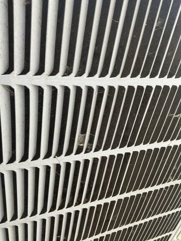 Completed comprehensive tune-up service on air conditioning system over 10 years old. Inspected condenser coil and found moderate accumulation of organic debris, including dried leaves and plant material lodged between fins, along with dust and lint buildup on heat exchanger surfaces. Cleaned exterior coil assembly and removed debris from ventilation spaces to restore proper airflow and heat transfer efficiency. Unit operational upon completion of service.