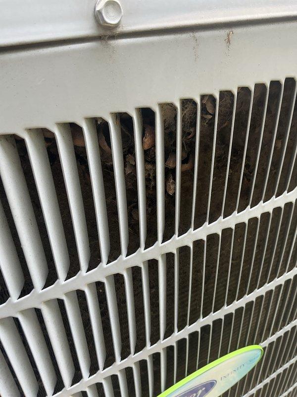 Completed comprehensive tune-up service on air conditioning system over 10 years old. Inspected condenser coil and found moderate accumulation of organic debris, including dried leaves and plant material lodged between fins, along with dust and lint buildup on heat exchanger surfaces. Cleaned exterior coil assembly and removed debris from ventilation spaces to restore proper airflow and heat transfer efficiency. Unit operational upon completion of service.