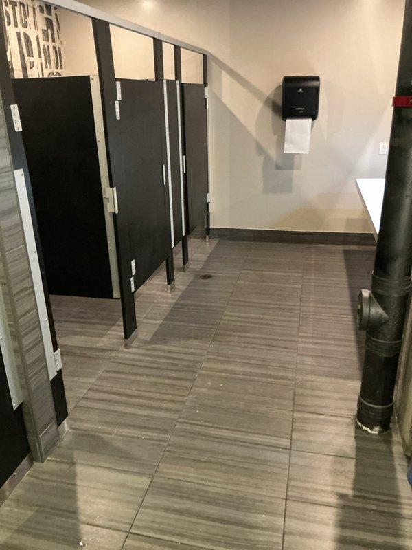 Responded to service call for toilet leaking at base during flushing in commercial restroom facility. This was the far left toilet in a three-stall configuration, with a previous service visit addressing a similar issue on another toilet in the same restroom. Upon arrival, inspected the affected floor-mounted toilet and identified water seepage at the base connection point. Removed toilet to access the wax ring seal and flange assembly. Found deteriorated wax ring allowing water to bypass the seal during flush cycles. Cleaned the toilet base and floor flange of old wax residue and debris. Inspected closet flange for cracks or damage and confirmed structural integrity. Installed new wax ring seal with proper compression. Repositioned toilet onto flange, ensuring proper alignment with mounting bolts. Torqued closet bolts to manufacturer specifications to create watertight seal without over-compression. Reconnected water supply line and tested flush mechanism multiple times to verify leak