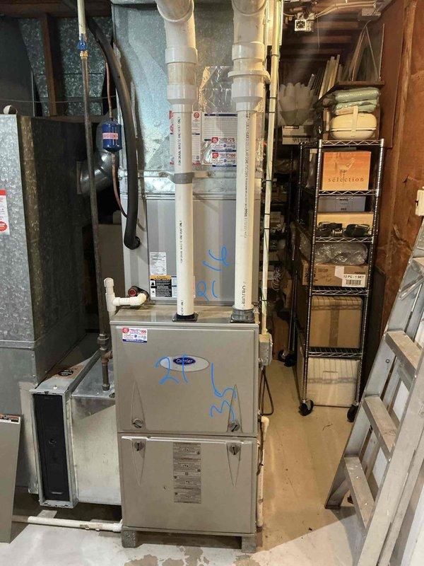 Conducted comprehensive evaluation of existing HVAC system for replacement estimate. Assessed outdoor condensing unit displaying weathering and dirt accumulation, documented model 3812E18385 with serial number 24HN873G, verified TXV metering device and electrical specifications, confirmed AHRI certification. Inspected indoor furnace installation in basement mechanical room, evaluated vertical furnace unit with PVC venting system, examined adjacent air handling equipment with associated refrigerant lines and shut-off valves. Photographed equipment specifications, installation conditions, and surrounding mechanical space to prepare detailed replacement proposal for complete system upgrade.