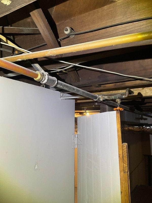 Completed diagnostic inspection of residential plumbing system to assess requirements for new washer/dryer water line installation and replacement of deteriorated galvanized piping in basement. Documented existing copper supply lines, heavily corroded galvanized vertical stack with extensive rust degradation, and current pipe routing through floor joists and structural framing to provide accurate quote for water line extension to proposed appliance location and full galvanized pipe replacement throughout basement area.