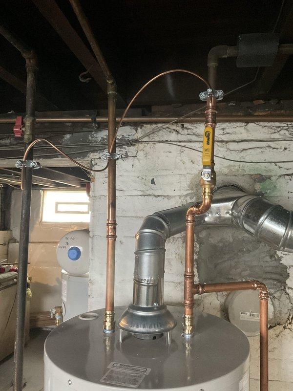 Replaced existing Bradford White residential water heater with new unit in basement utility area. Removed old water heater dated from 2014 and installed replacement gray cylindrical water heater. Connected copper supply and discharge piping to new unit with proper fittings and joints. Installed pressure relief valve with discharge pipe per code requirements. Connected metal exhaust vent pipe for proper combustion gas venting. Verified all plumbing connections for leaks and tested unit operation to ensure proper heating functionality.