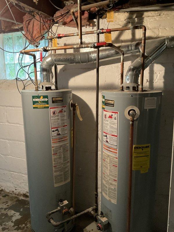 Responded to service call for leaking water heater in 112-year-old residence. Upon inspection, identified significant water leakage at base connections with visible corrosion on threaded pipe fittings and elbow joints, evidenced by orange-rust staining on concrete floor beneath unit. Assessed aged metal plumbing infrastructure showing oxidation and deterioration consistent with extended service life. Performed necessary repairs to eliminate active leak, addressed corroded connections, and verified proper operation of unit. System tested and confirmed leak-free upon completion.