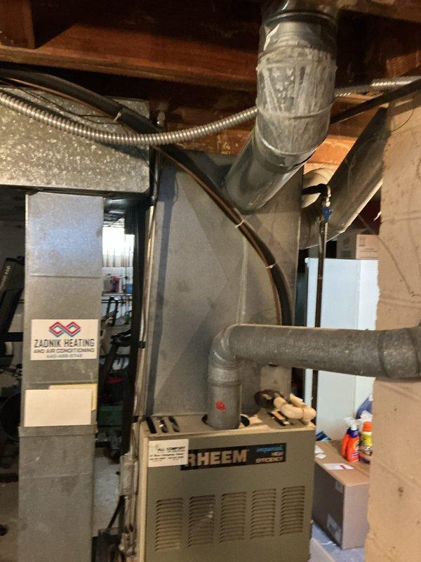 Responded to service call for air conditioning system blowing warm air. Diagnosed non-functional condenser fan on 10+ year old outdoor unit while indoor blower operated normally. Assessed existing Rheem furnace and HVAC system configuration in basement mechanical room. Provided comprehensive replacement estimate including equipment specifications, placement requirements per property layout, and installation scope for new condensing unit to restore cooling functionality.