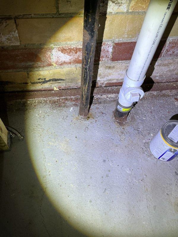 Responded to report of rust spots and leaking on basement sewage stack. Upon inspection, identified corrosion and active leak on cast iron waste stack near floor penetration. Documented existing conditions showing deteriorated pipe sections with visible rust staining on masonry wall and floor area. Photographed affected plumbing infrastructure including waste stack, adjacent water lines, and structural mounting points for assessment and repair recommendation purposes.