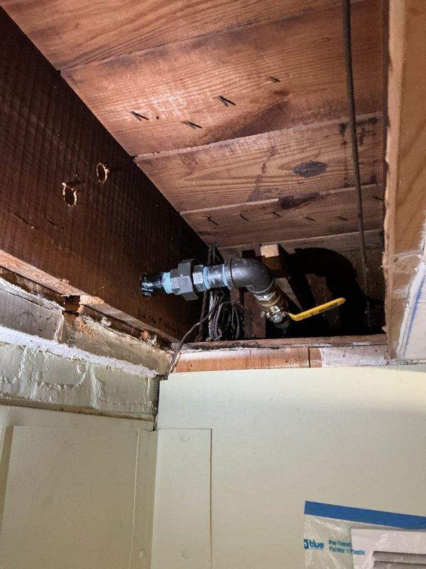 Installed 1.25" x 1" tee fitting in existing gas line system and ran corrugated stainless steel tubing (CSST) across ceiling joists to back wall location. Transitioned from CSST to rigid black iron pipe, then ran polyethylene (PE) pipe underground with two 90-degree sweep elbows and capped termination point to complete gas line extension.