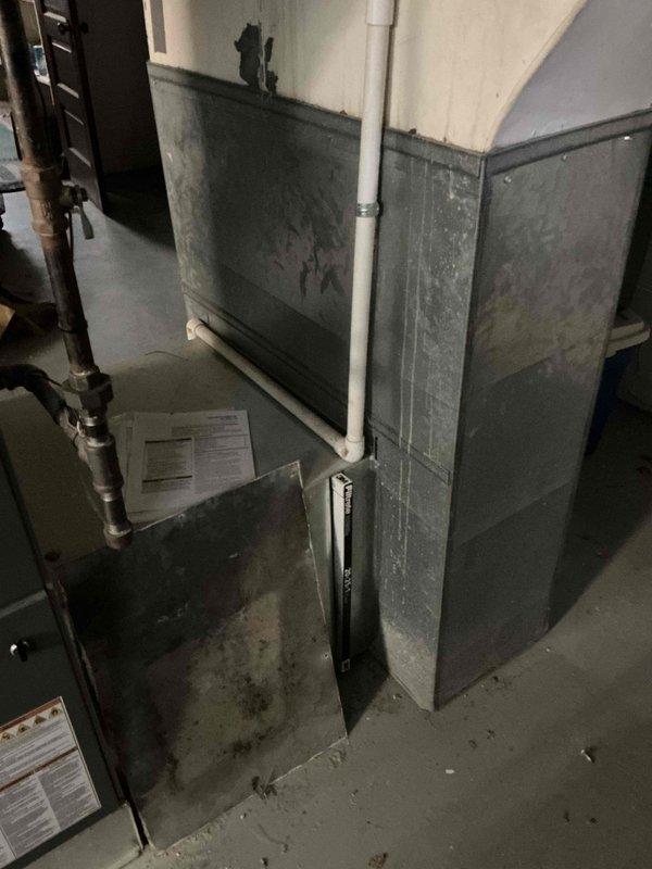 Performed comprehensive evaluation of 30+ year old residential HVAC system located in basement mechanical room. System showed significant age-related deterioration with visible dirt accumulation, surface discoloration, and dark streaking on air handler panels. Assessed existing gray metal air handler/furnace unit with associated ductwork and electrical connections. Documented equipment condition through photography, noting exposed ceiling joists, concrete flooring, and proximity to water heater with copper piping. Provided detailed replacement estimate for aging system that had previously been evaluated by two other contractors.