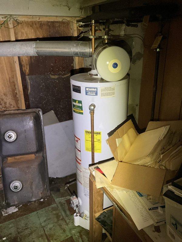 Responded to emergency service call for severely leaking tanked water heater causing extensive water damage and hazardous mold conditions in basement utility area. Upon arrival, found standing water pooling around base of water heater with significant floor saturation and visible deterioration of concrete surfaces. Shut off water supply to failed water heater to stop active leak and prevent further water intrusion. Documented hazardous conditions including contaminated standing water, moisture damage to surrounding surfaces, and compromised indoor air quality requiring protective respiratory equipment during service.